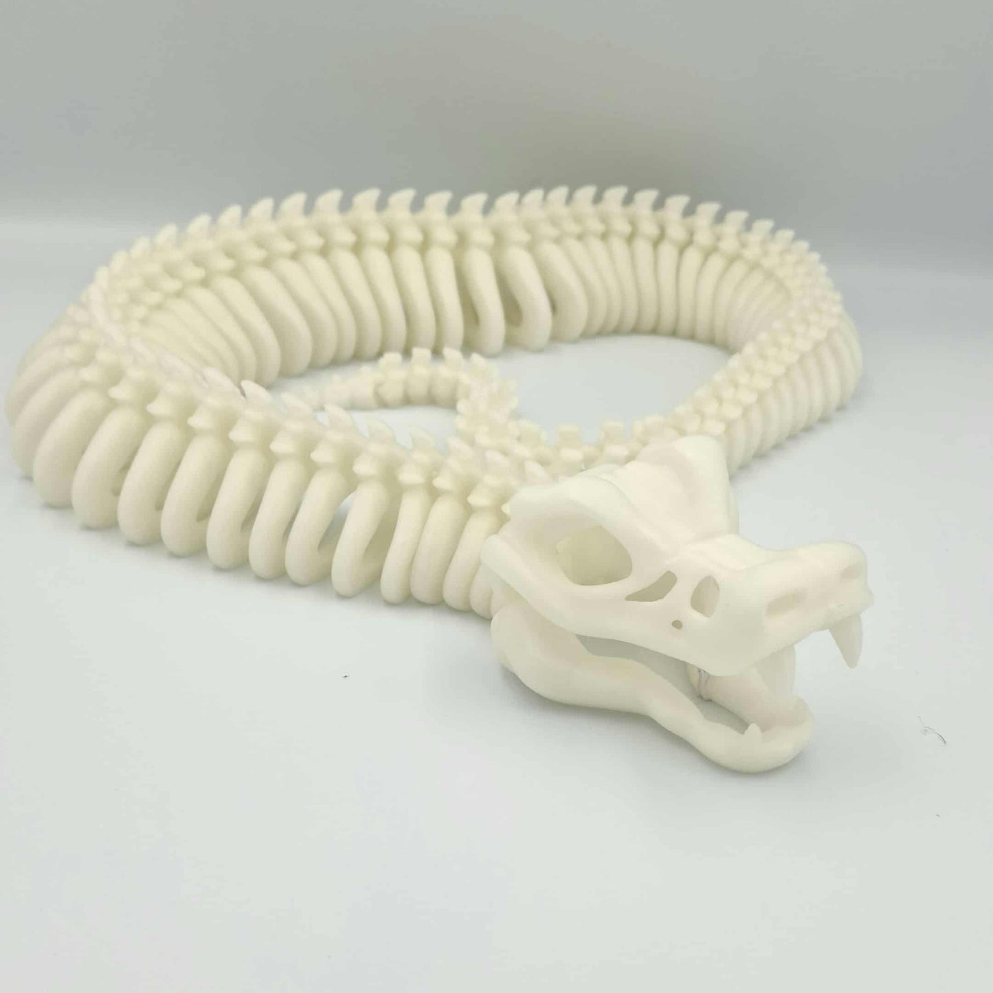 3D printed articulated skeleton snake in black and red gradient with poseable body and an opening jaw.