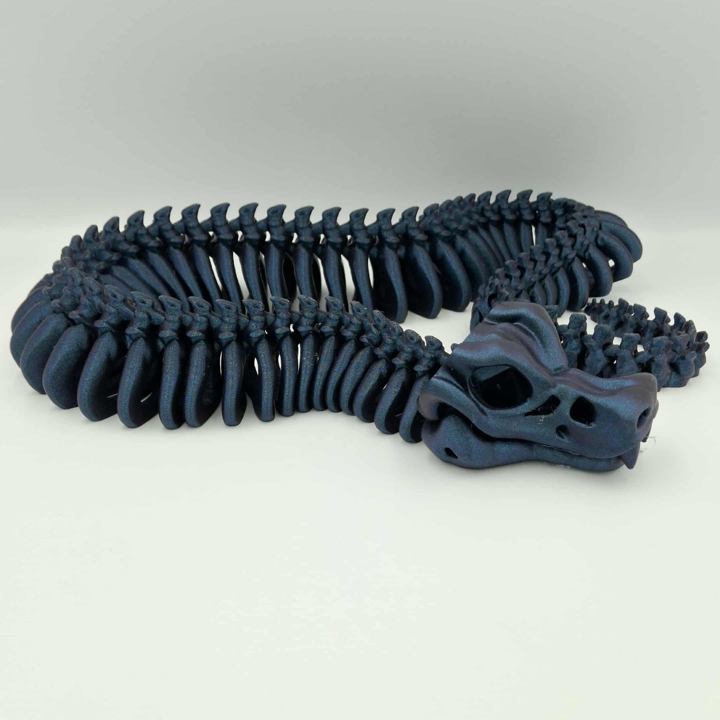 3D printed articulated skeleton snake in black and red gradient with poseable body and an opening jaw.