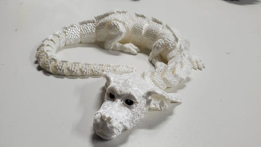 “White articulated 3D printed luck dragon figure with moving head, feet, and flexible body – detailed fantasy model.”